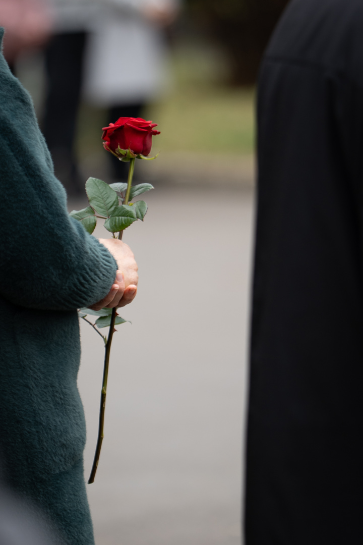 A mourner holding a red rose