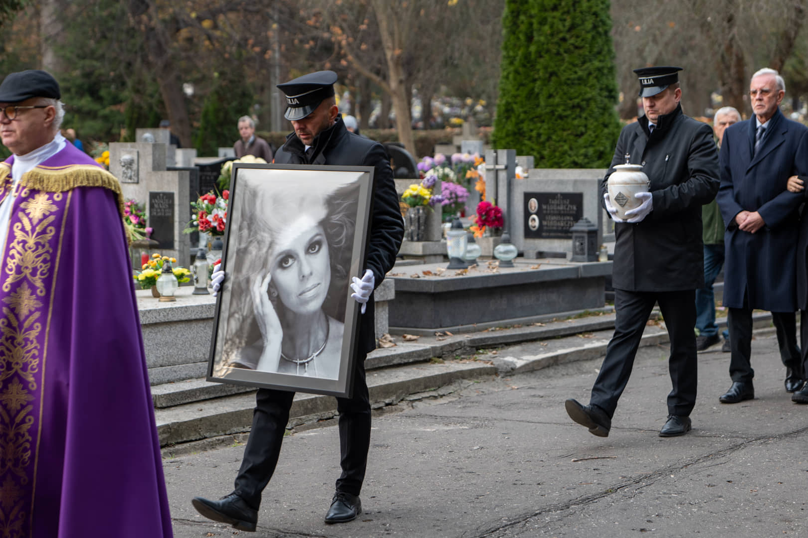 A Lilia bearer carries a portrait of the deceased in a funeral procession at the cemetery
