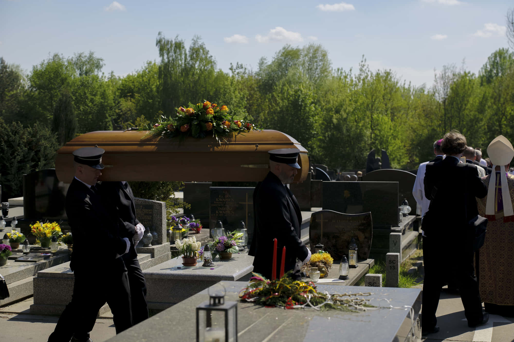 Lilia staff carrying a coffin at a cemetery
