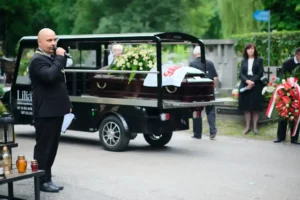 The celebrant speaking beside the cart carrying the coffin