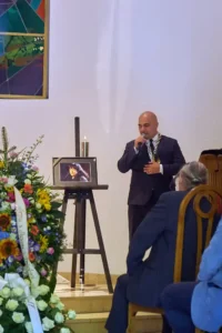 The celebrant speaking beside a portrait of the deceased