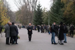 Mourners in a cemetery avenue, the celebrant among them