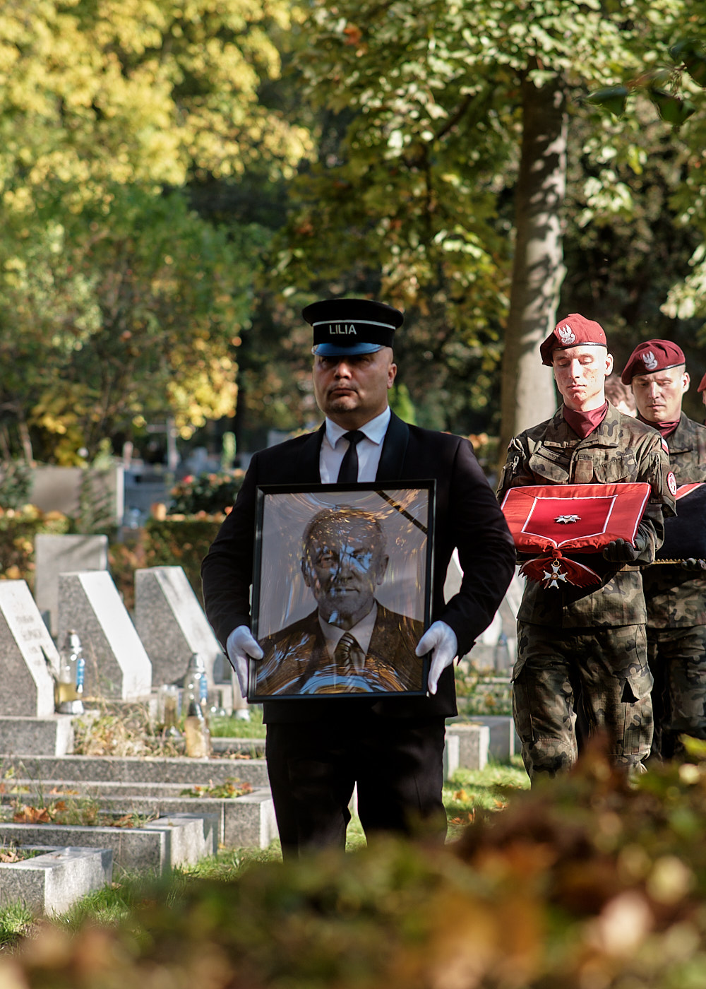 A Lilia staff member carries a portrait of the deceased during a funeral service
